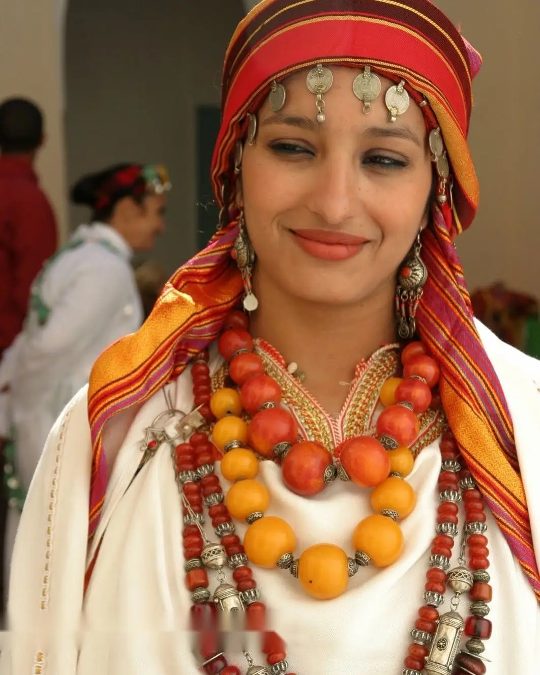 Amazigh woman wearing traditional amber and coral bead necklaces with silver jewellery and a striped headscarf