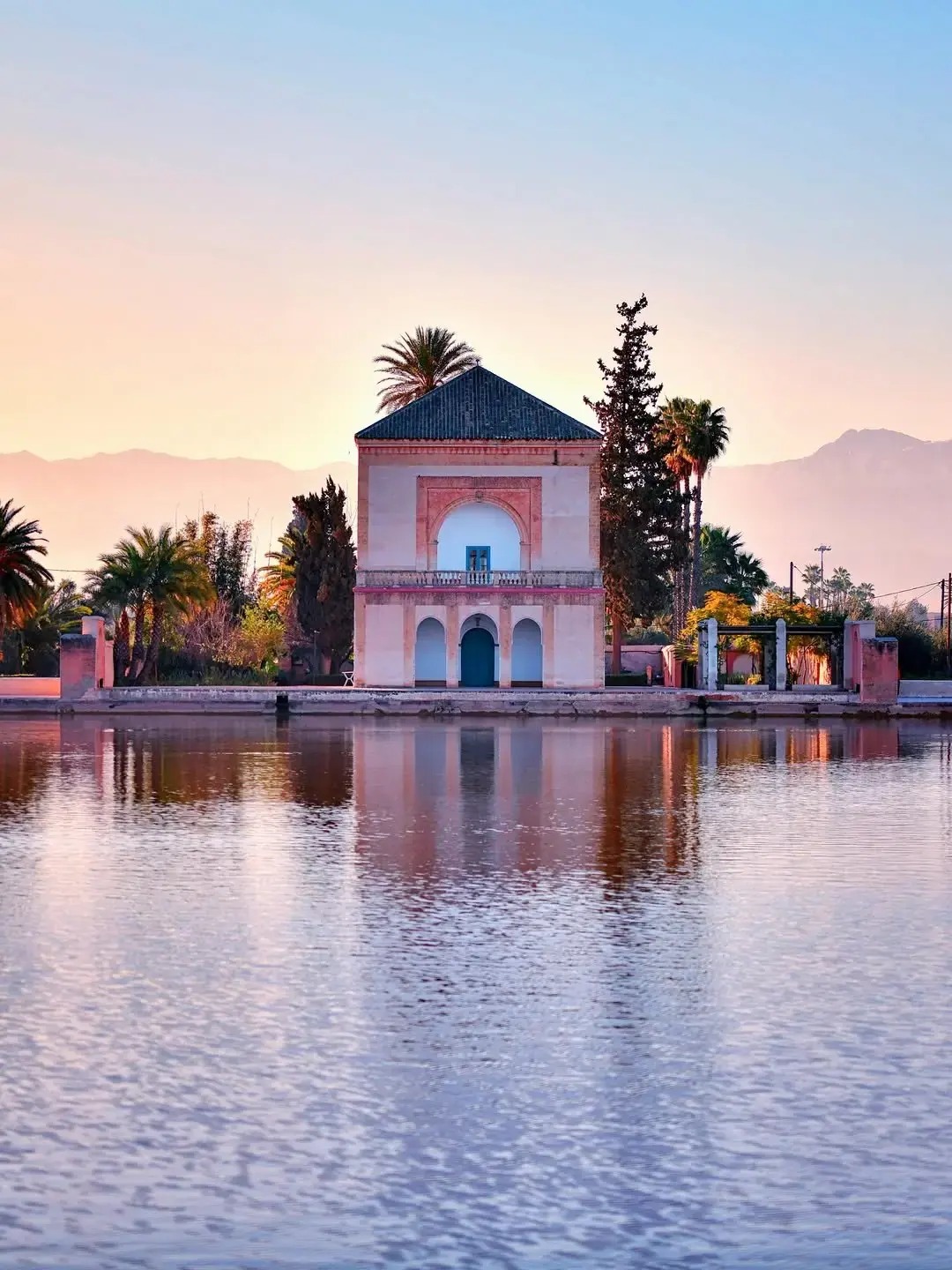 The green-tiled Menara pavilion reflected in its basin with the Atlas behind, Marrakech