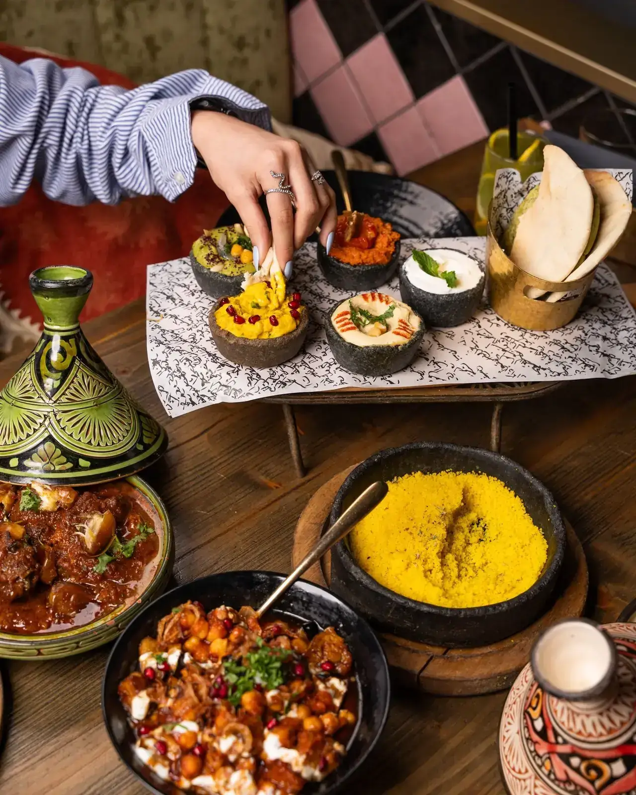 Moroccan mezze spread with dips, couscous and tagine dishes on a wooden table