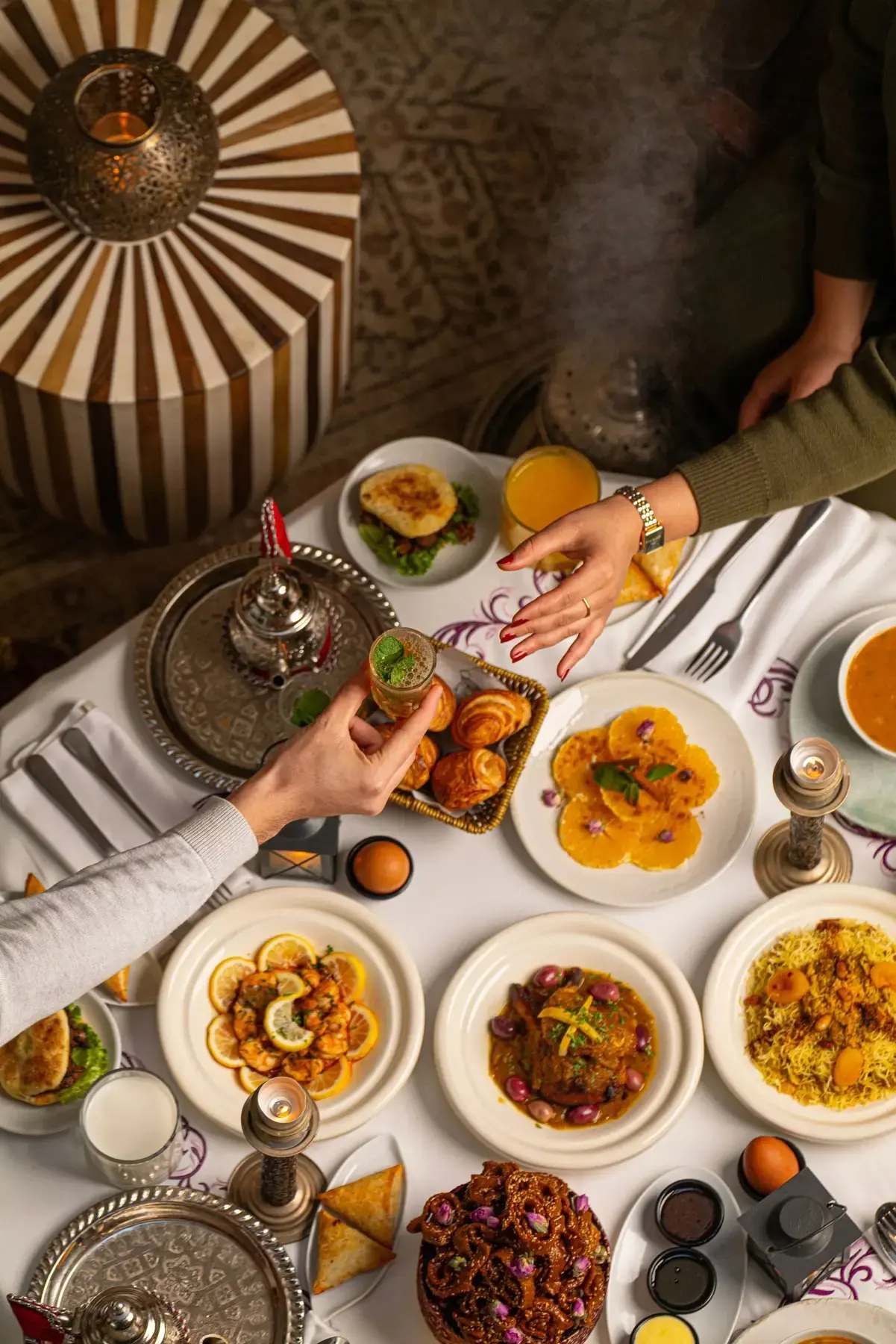 Guests sharing a glass of mint tea across a richly laid riad dining table