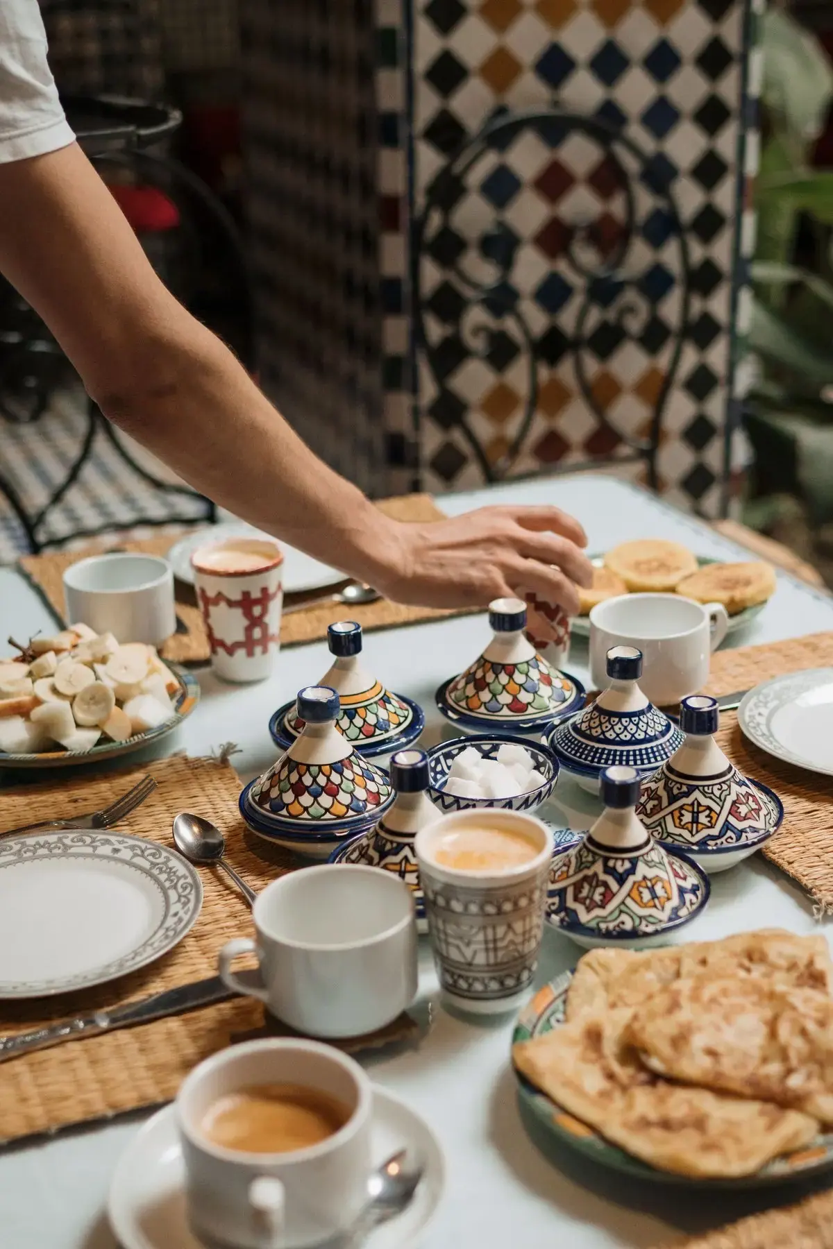 Riad breakfast table with msemen flatbread, hand-painted ceramic tagine servers and coffee