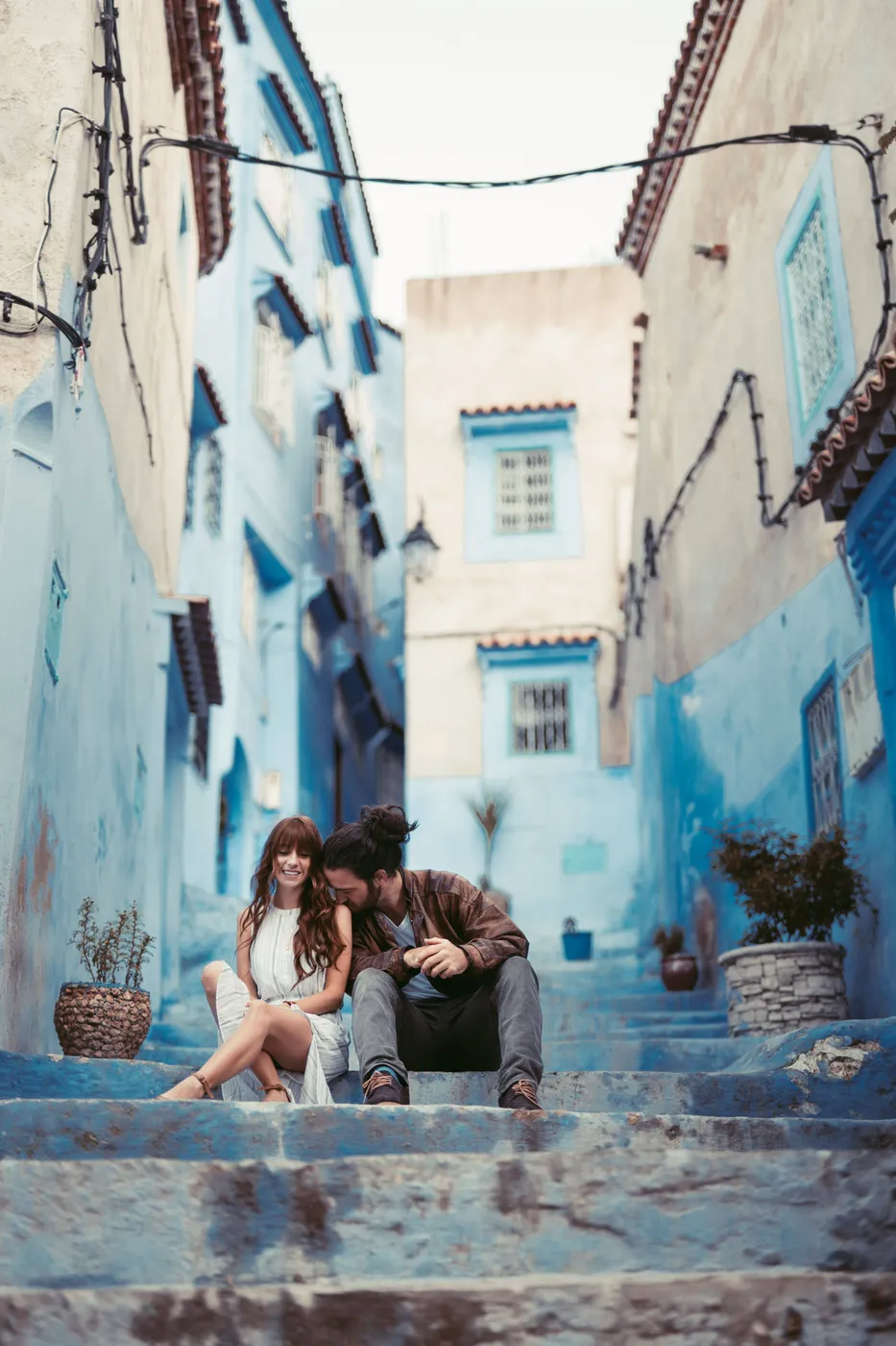 Couple walking down blue-painted steps in the Chefchaouen medina, Morocco