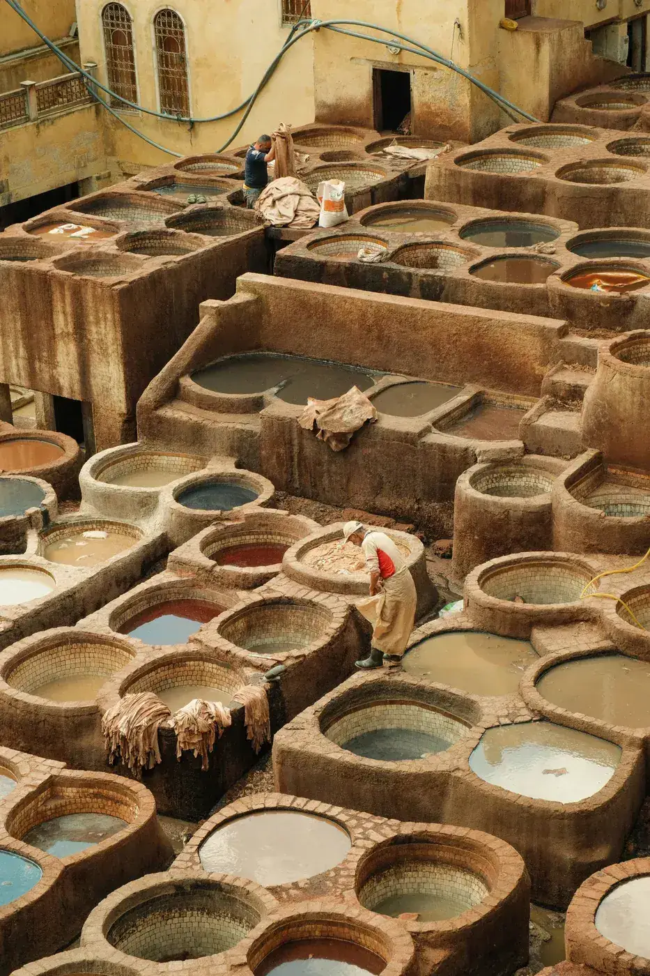 Workers treating leather hides among the dyeing pits of a traditional Fes tannery