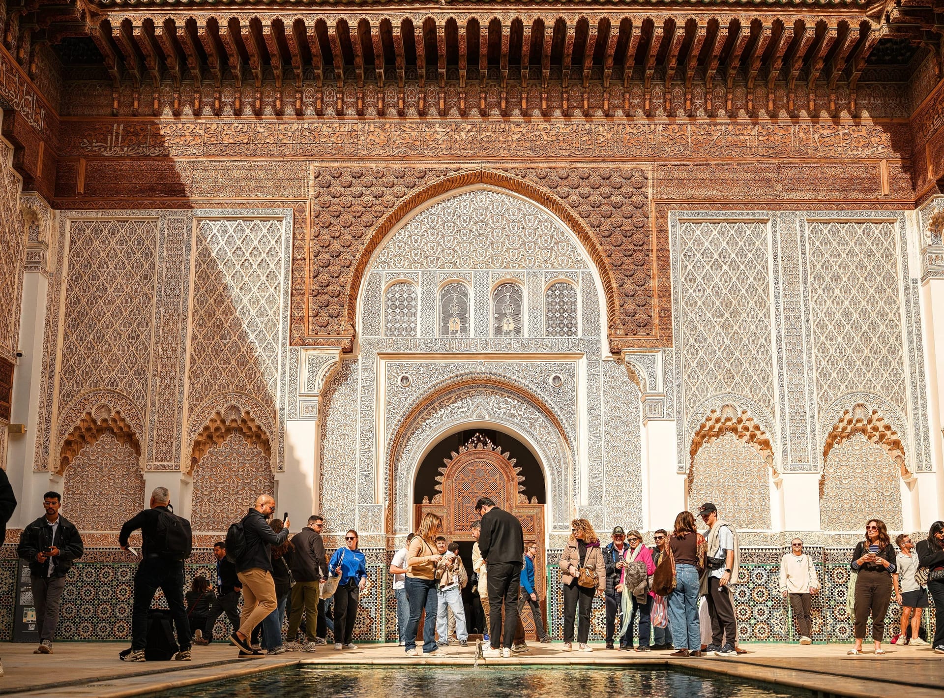 Tourists inside the ornate courtyard of Ben Youssef Madrasa in Marrakech