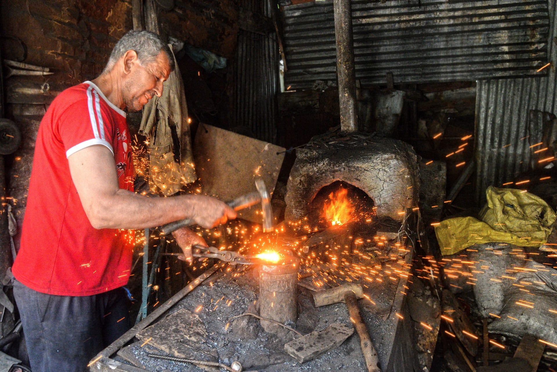 Moroccan blacksmith hammering hot metal with sparks flying — traditional medina forge