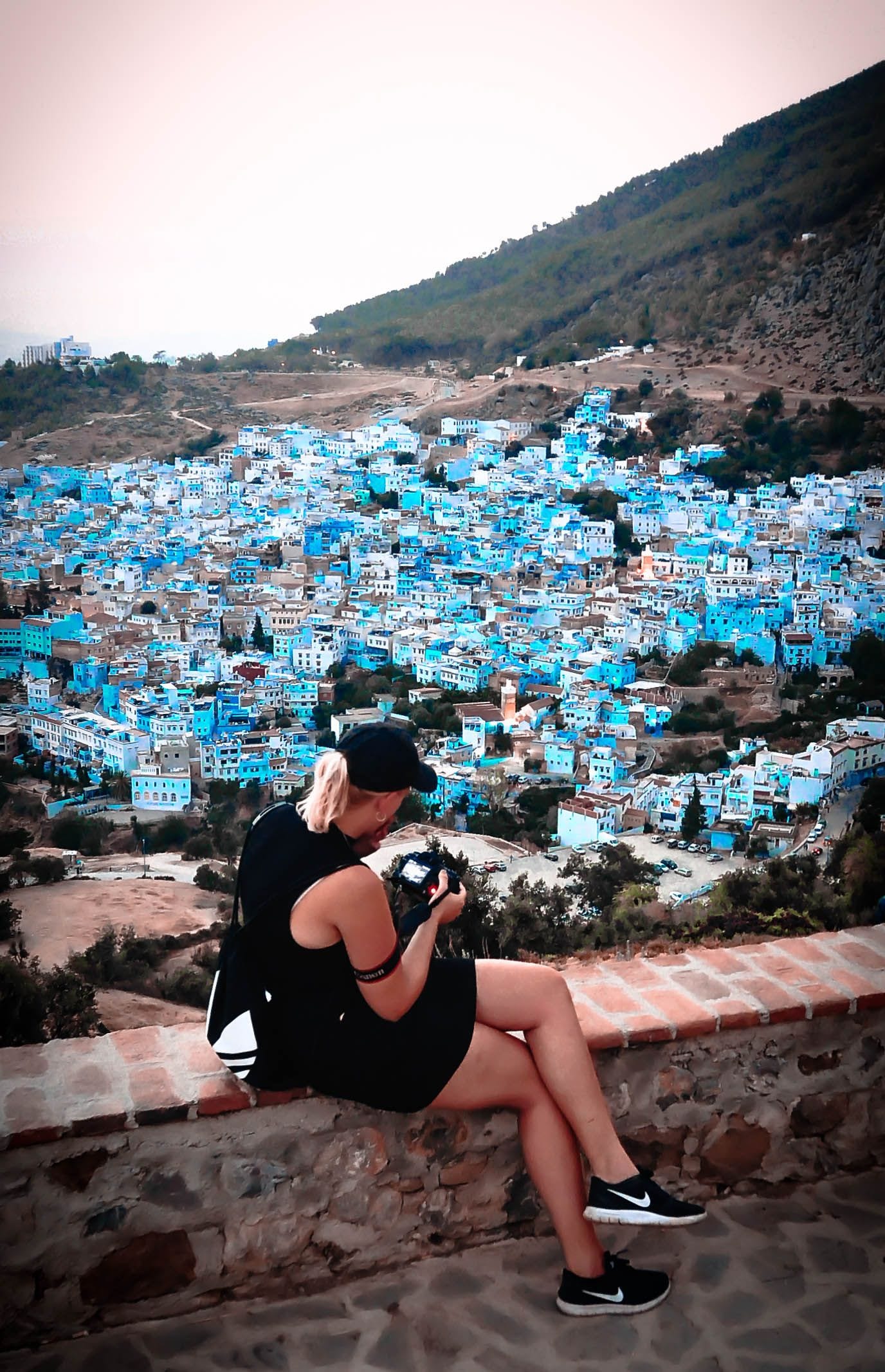 Tourist overlooking the iconic blue-painted buildings of Chefchaouen from above