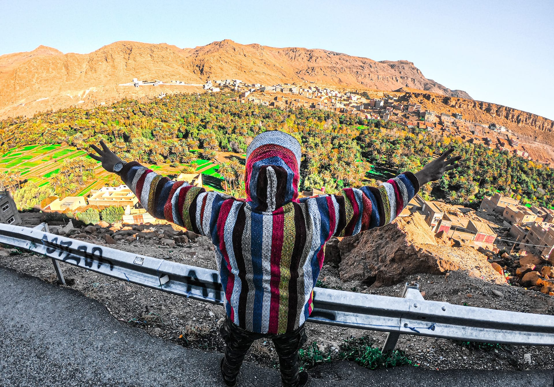Person in a djellaba with arms wide above the lush Dades Valley oasis from a viewpoint