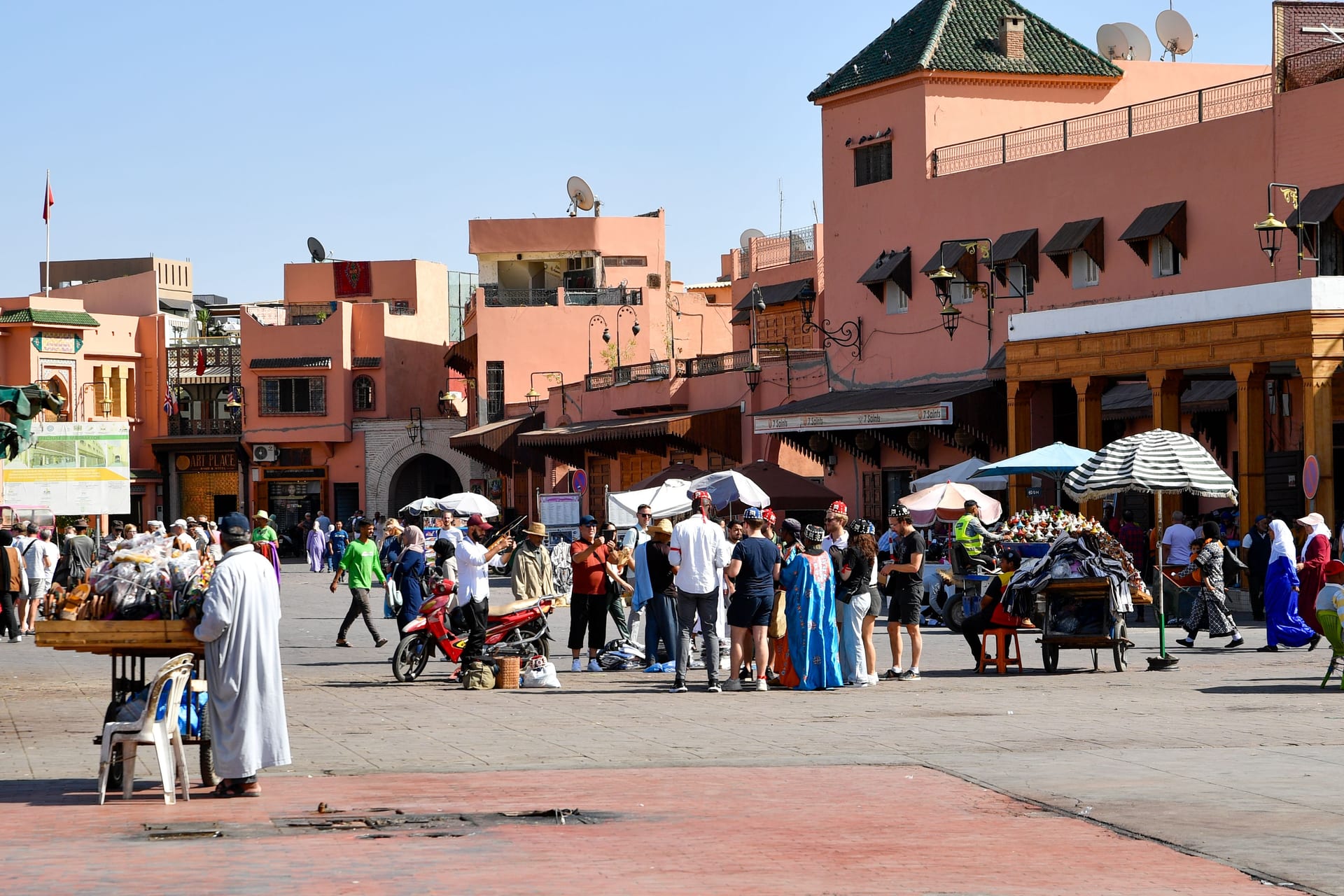 Daytime view of Jemaa el-Fna with vendors and terracotta buildings