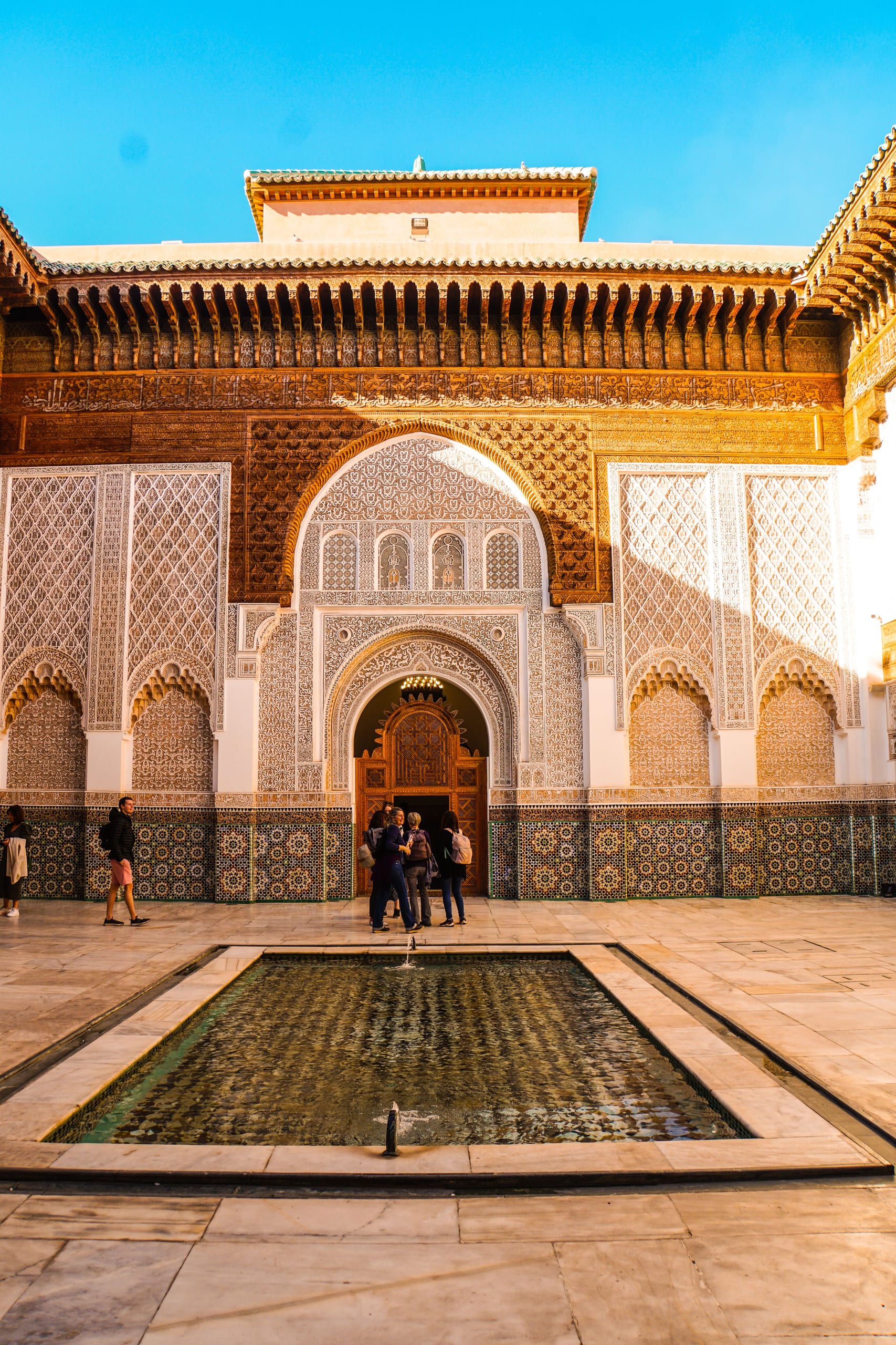 Madrasa courtyard at golden hour with ornate stucco and zellige tiles in Fes