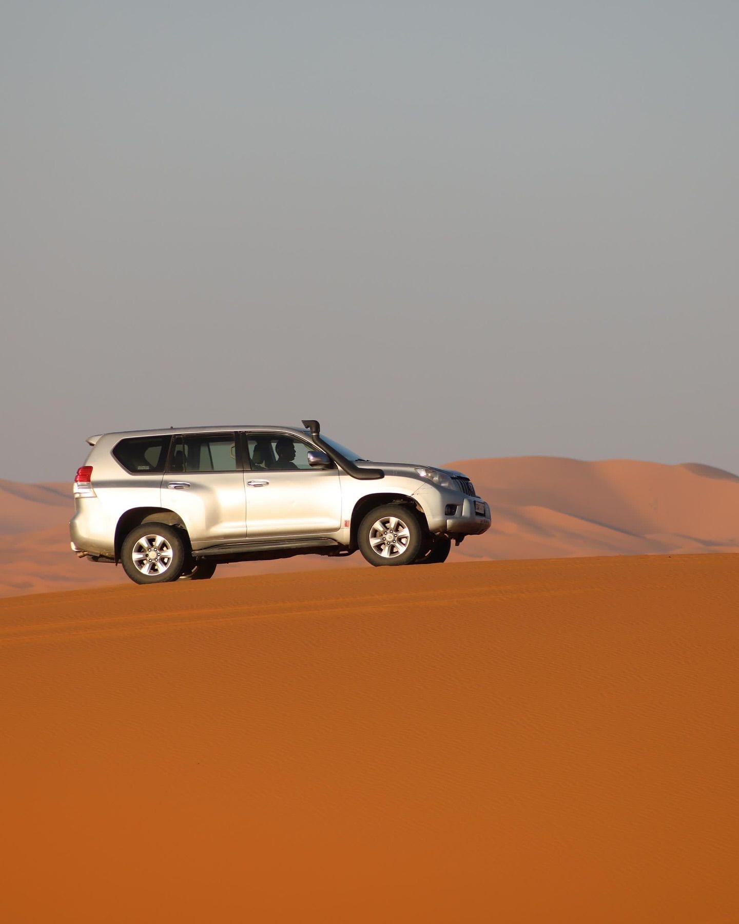 Silver Toyota Land Cruiser on a Sahara dune crest — private fleet hero image
