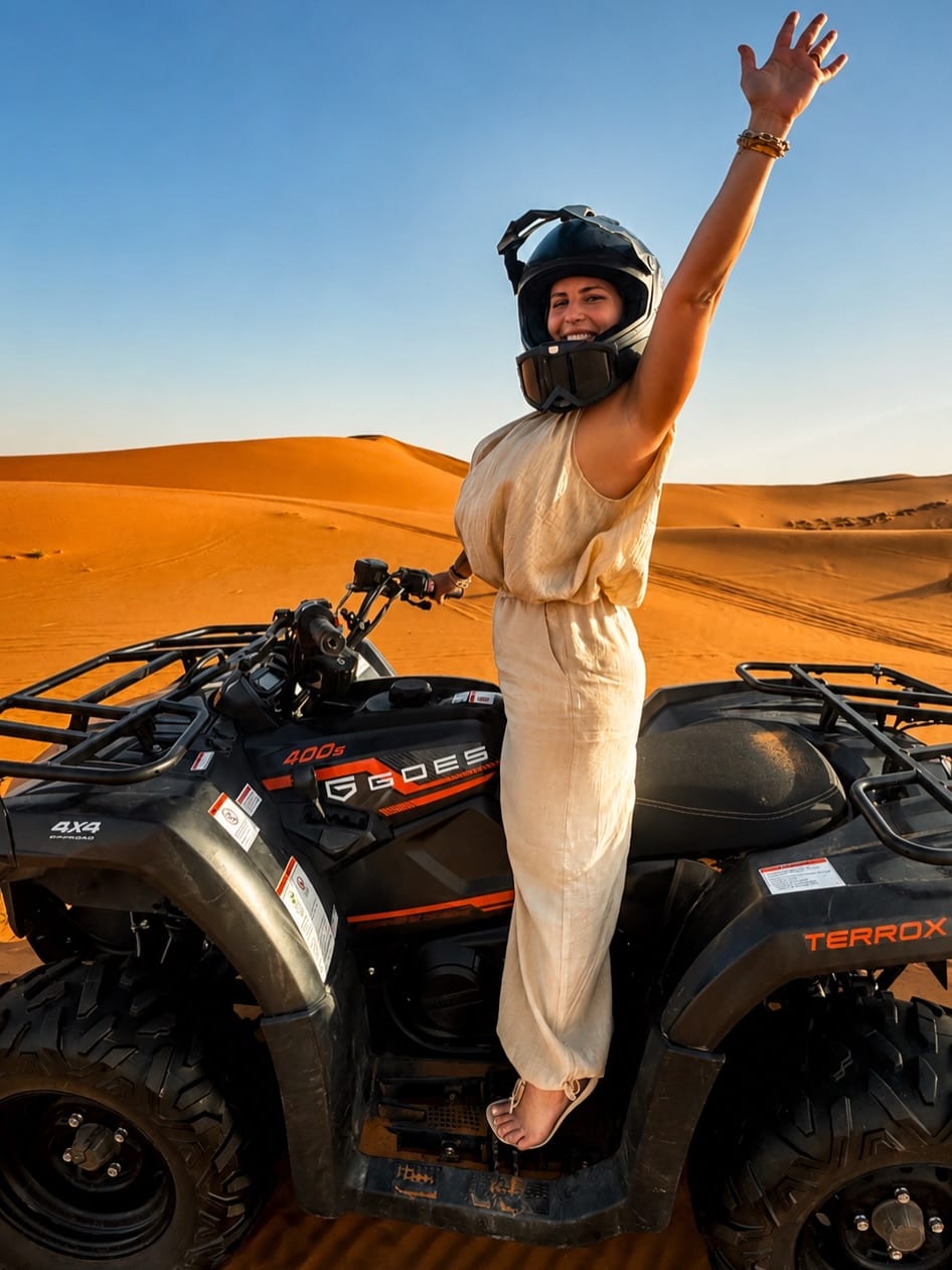 Joyful female tourist standing on a quad bike on the Erg Chebbi dunes