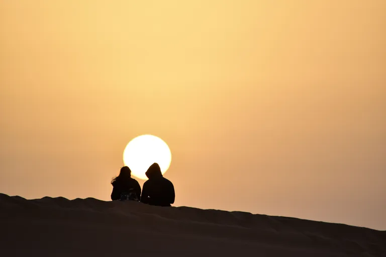 Silhouette of a couple watching sunset from an Erg Chebbi dune