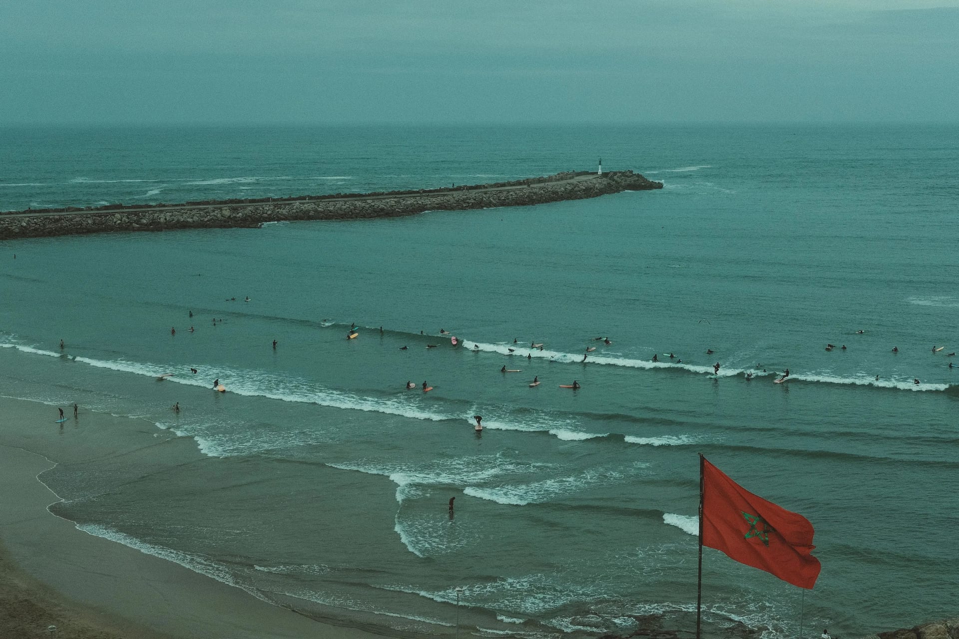 Aerial view of surfers in the Atlantic with a Moroccan flag in the foreground