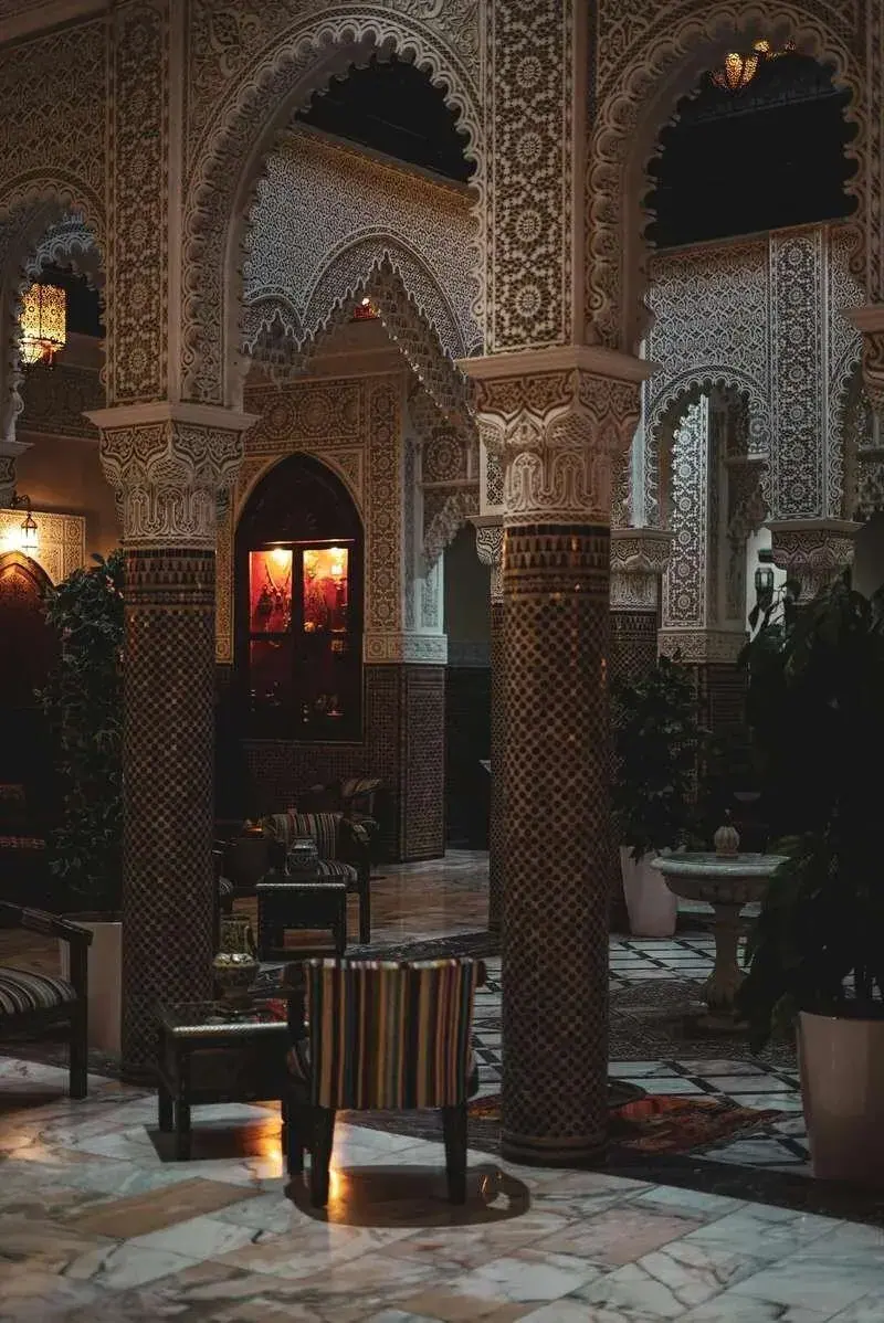 Ornate Moroccan riad courtyard with carved stone facades and potted plants