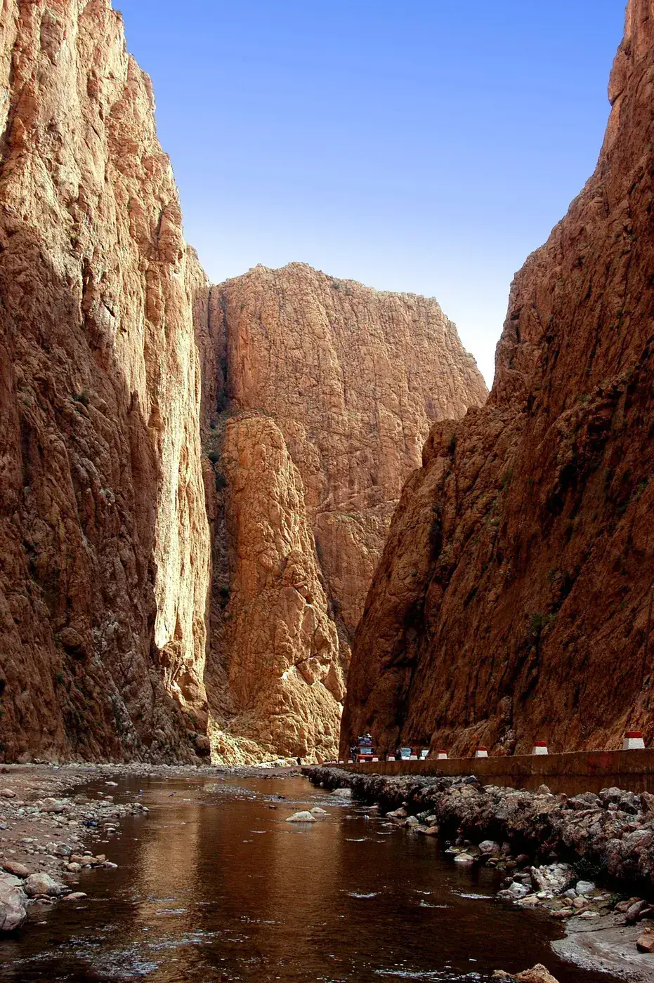 A shallow river running between the high red rock walls of a narrow gorge