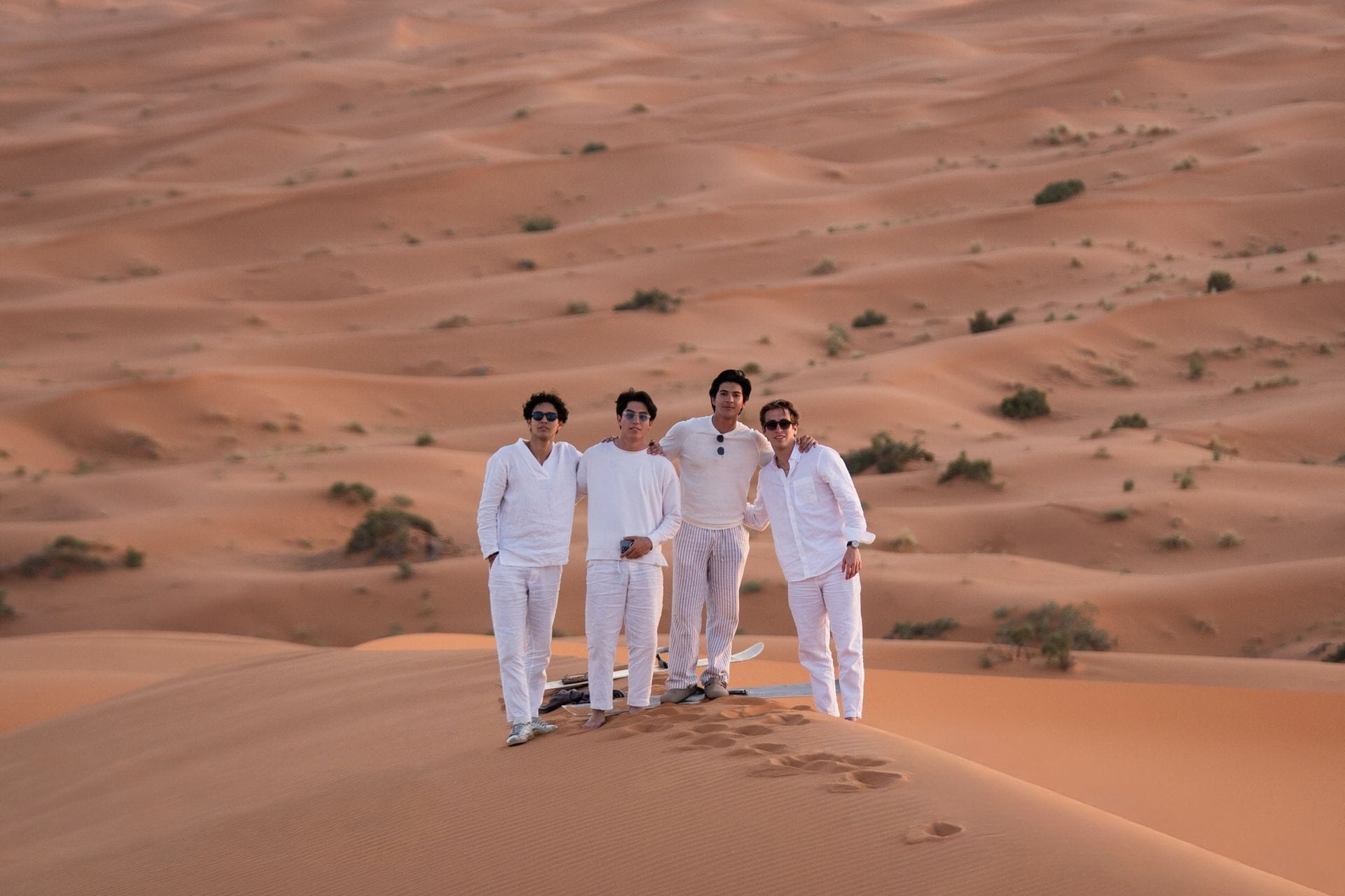 Four students in white standing on a dune crest in the Sahara